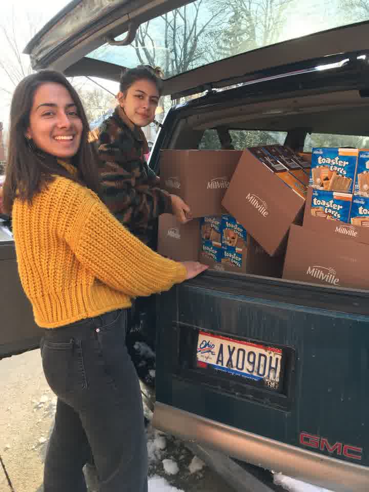 Students loading boxes of food into a car