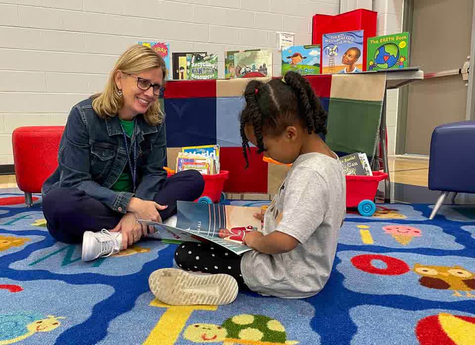 A parent and child reading together on a classroom rug